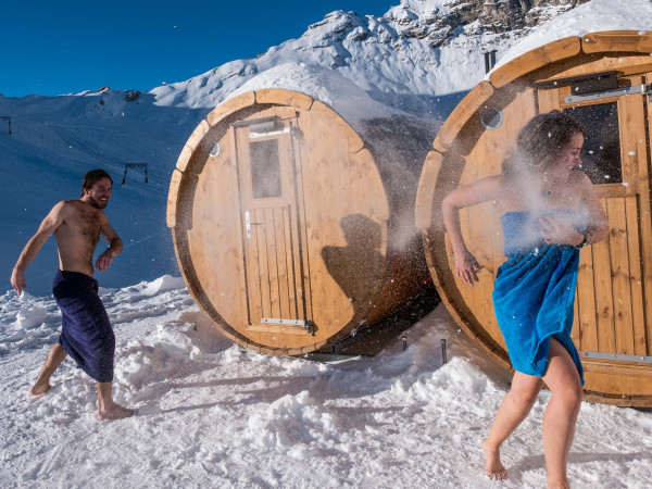 Ein Paar schiesst Schneebälle vor der Fasssauna im Iglu-Dorf
